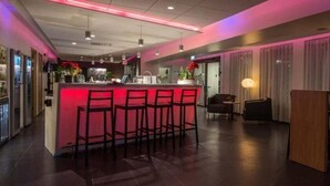 Un moderno vestíbulo de hotel con una zona de bar central, espacios de asiento y una recepción.
