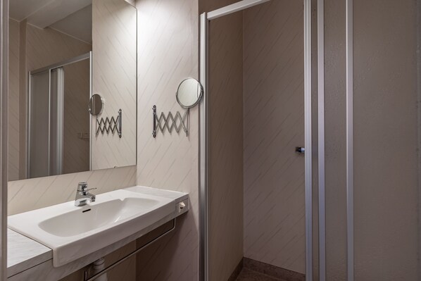 A bathroom with a white sink, a mirror, and a shower door. - Hotell Villa Sparta (Alvsbyn)