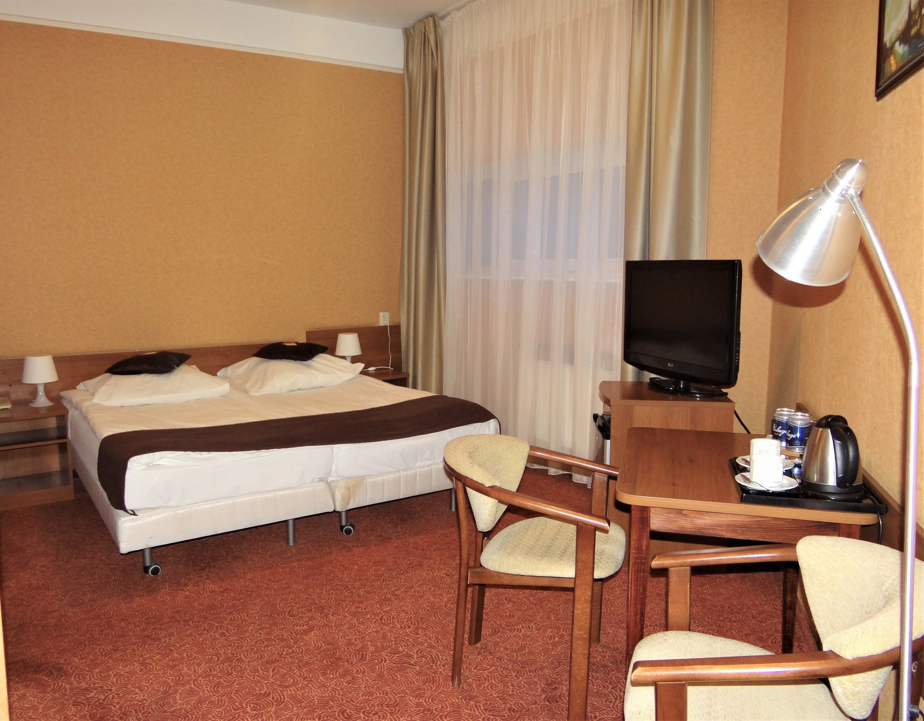 Une chambre d’hôtel équipée d’un lit, d’un bureau avec une télévision, d’une chaise et d’une machine à café.