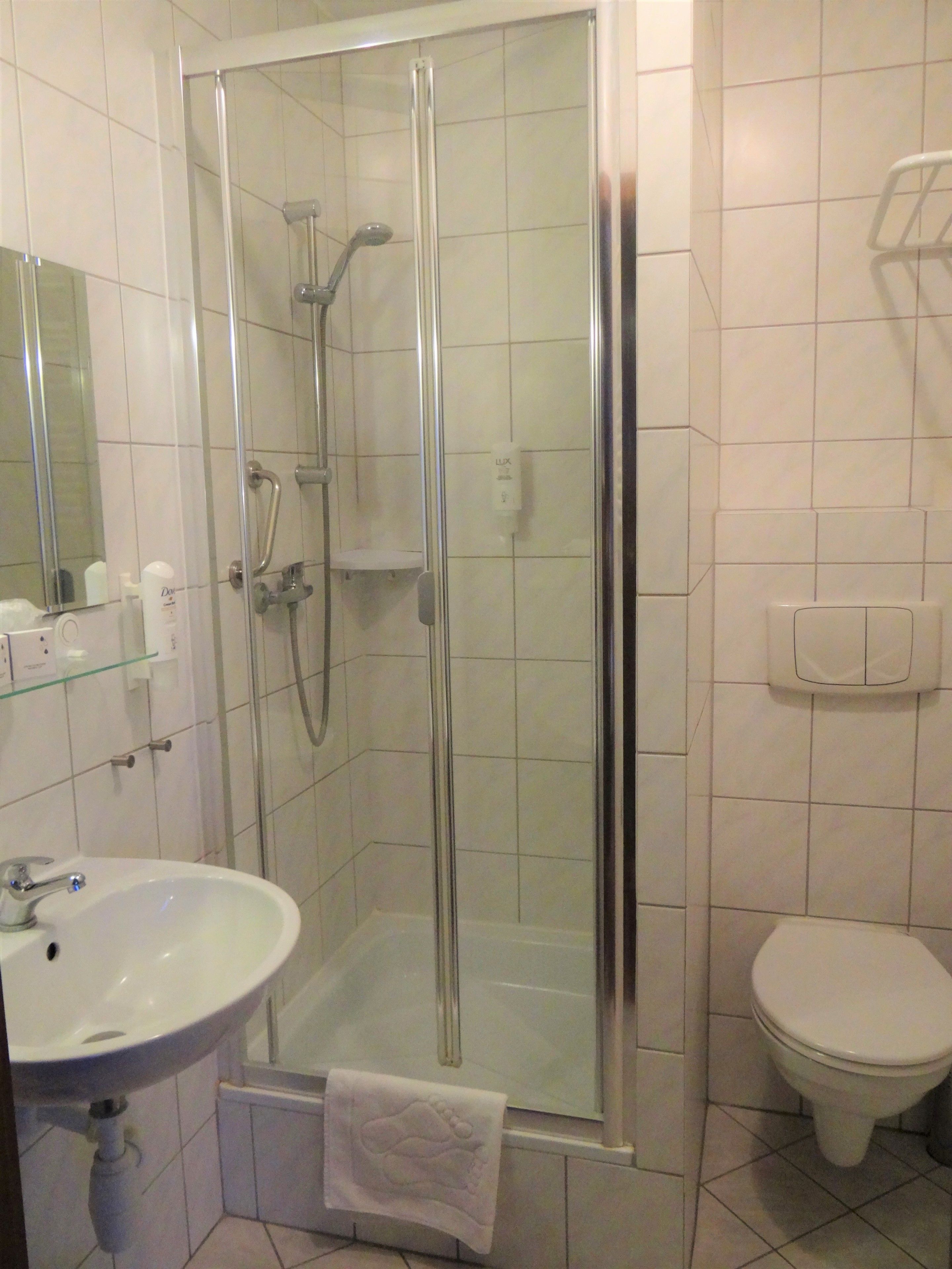 Un bagno con doccia in vetro, lavandino e WC.