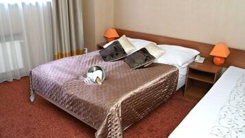 A hotel room with a large bed, two bedside tables, a nightstand, a lamp, and a telephone.