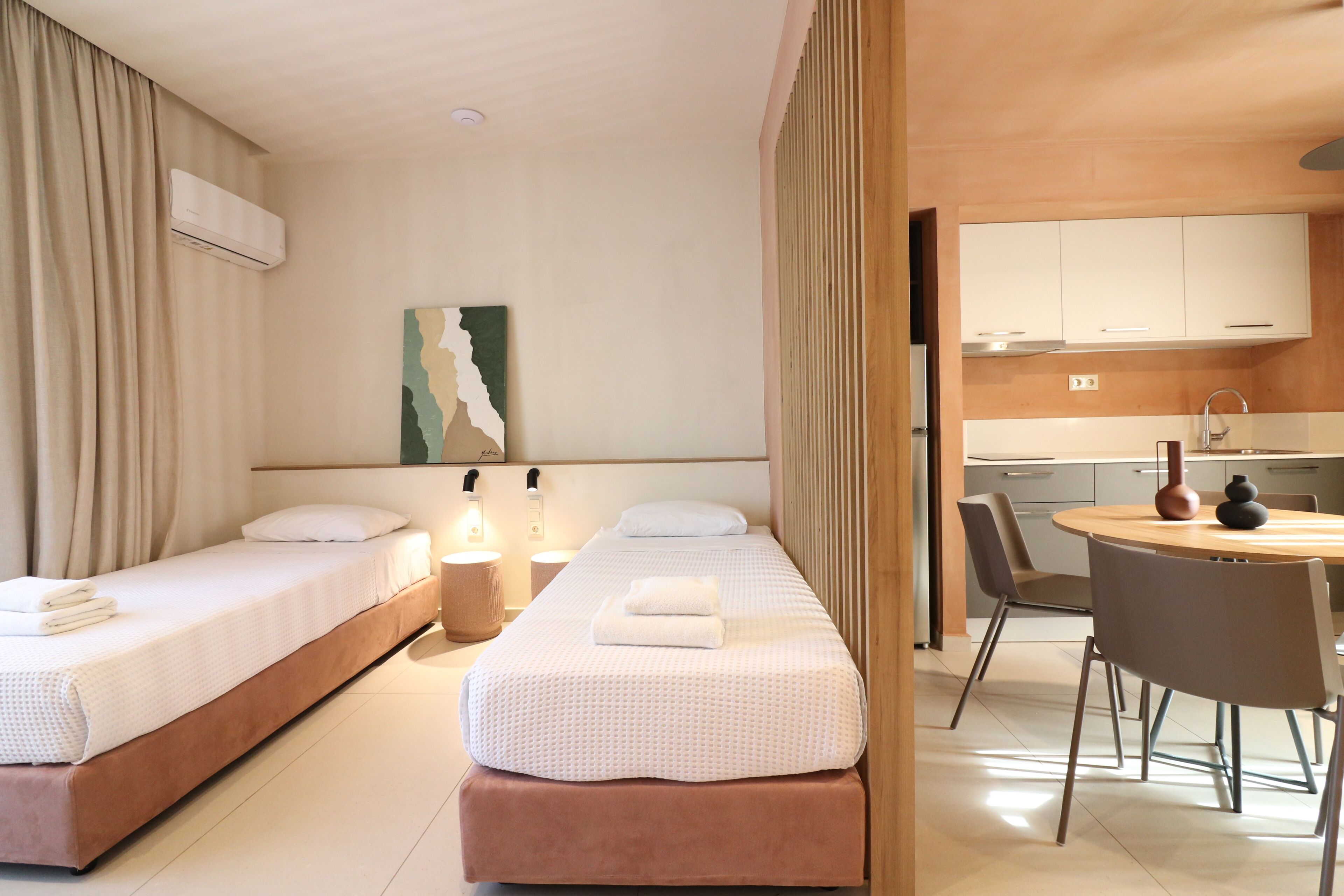 A hotel room with two beds, a dining area, and a kitchenette.