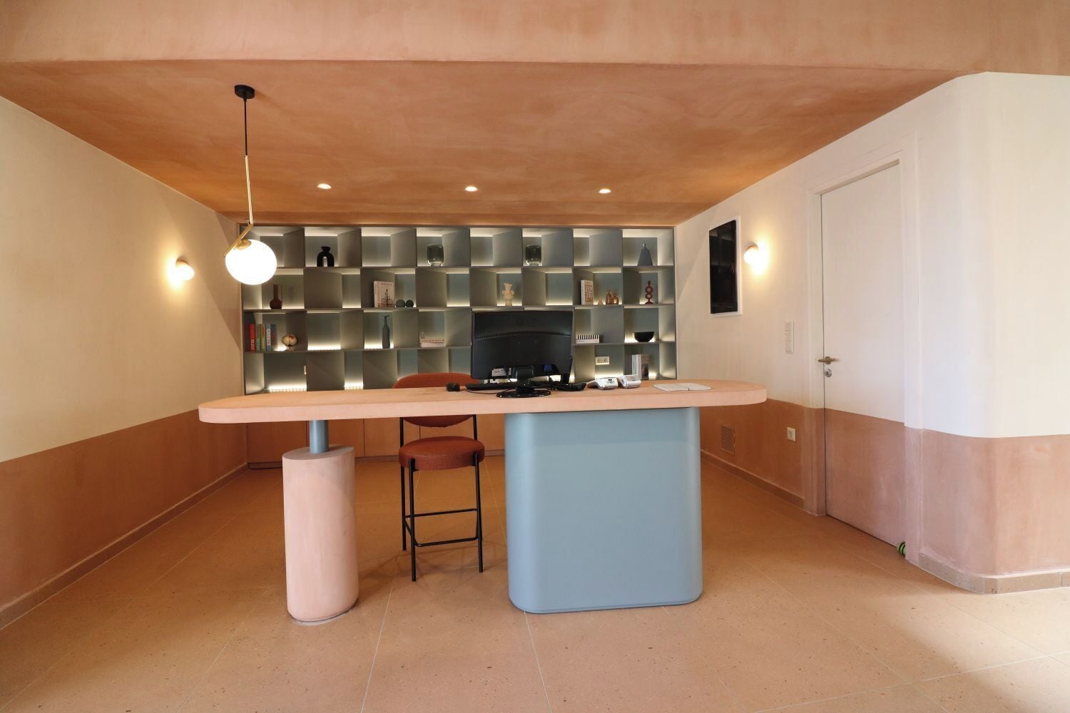 Una cocina moderna con una isla central, una estantería empotrada y una lámpara colgante.