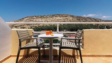 A balcony with two chairs and a table, overlooking a mountainous landscape.