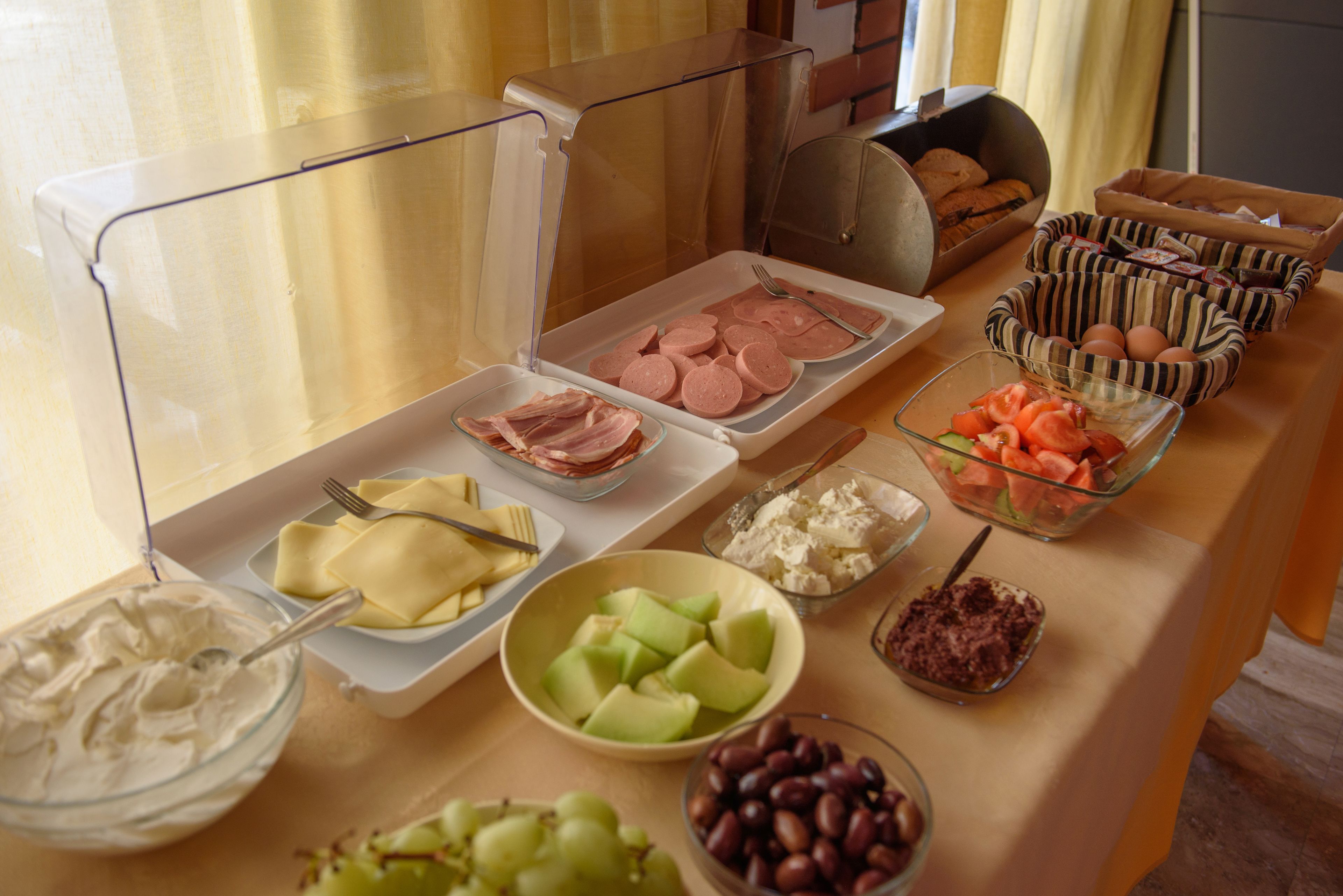 Een buffettafel met diverse gerechten, waaronder vleeswaren, kazen, fruit en olijven.