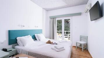 Une chambre d’hôtel équipée d’un lit, d’un bureau, d’une chaise, d’une télévision et d’une fenêtre donnant sur un paysage verdoyant.