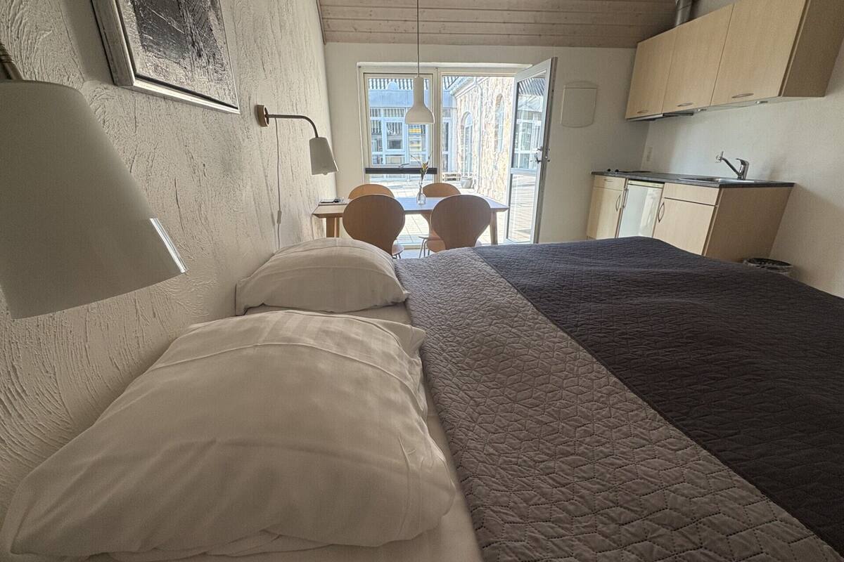 A bedroom with two beds, a desk, and a window.
