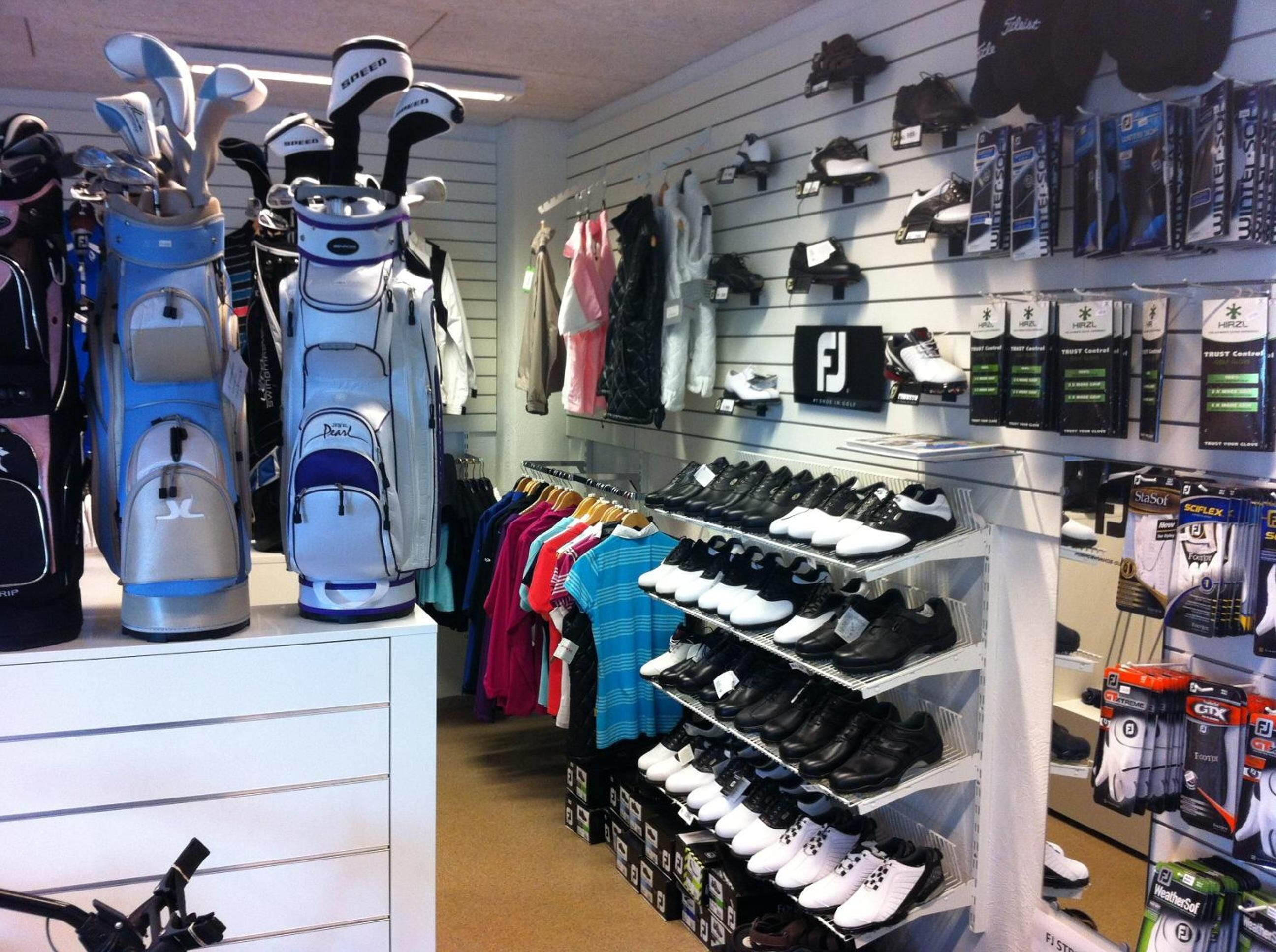 A golf equipment store with shelves of golf shoes, bags, and accessories.