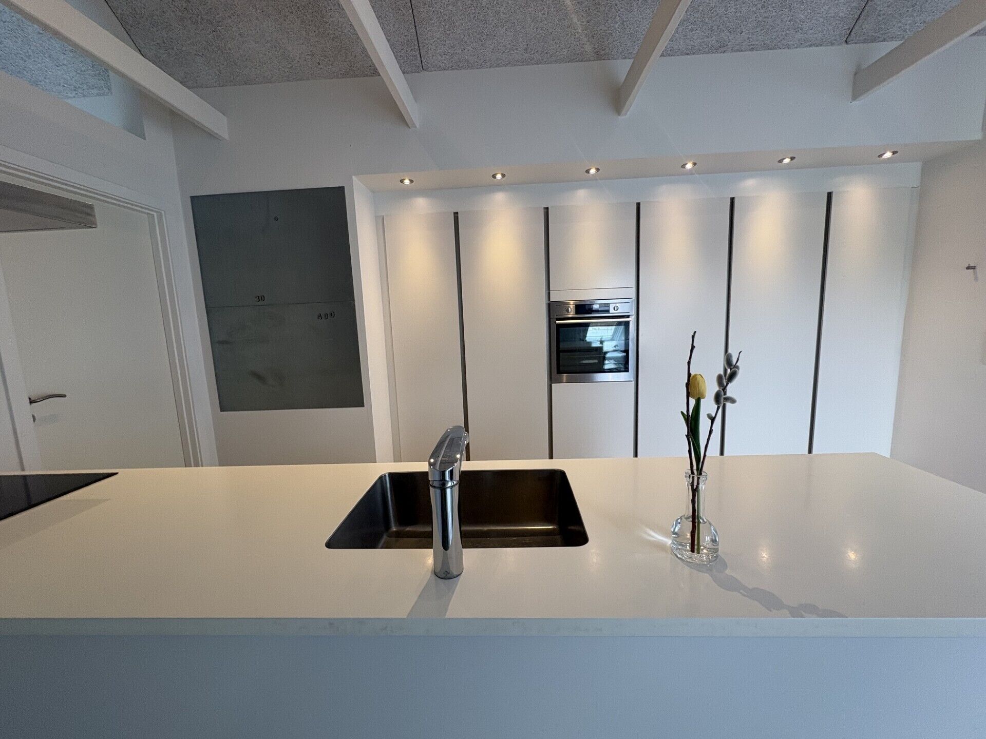 Cocina moderna con una isla central, horno empotrado y un grifo elegante.