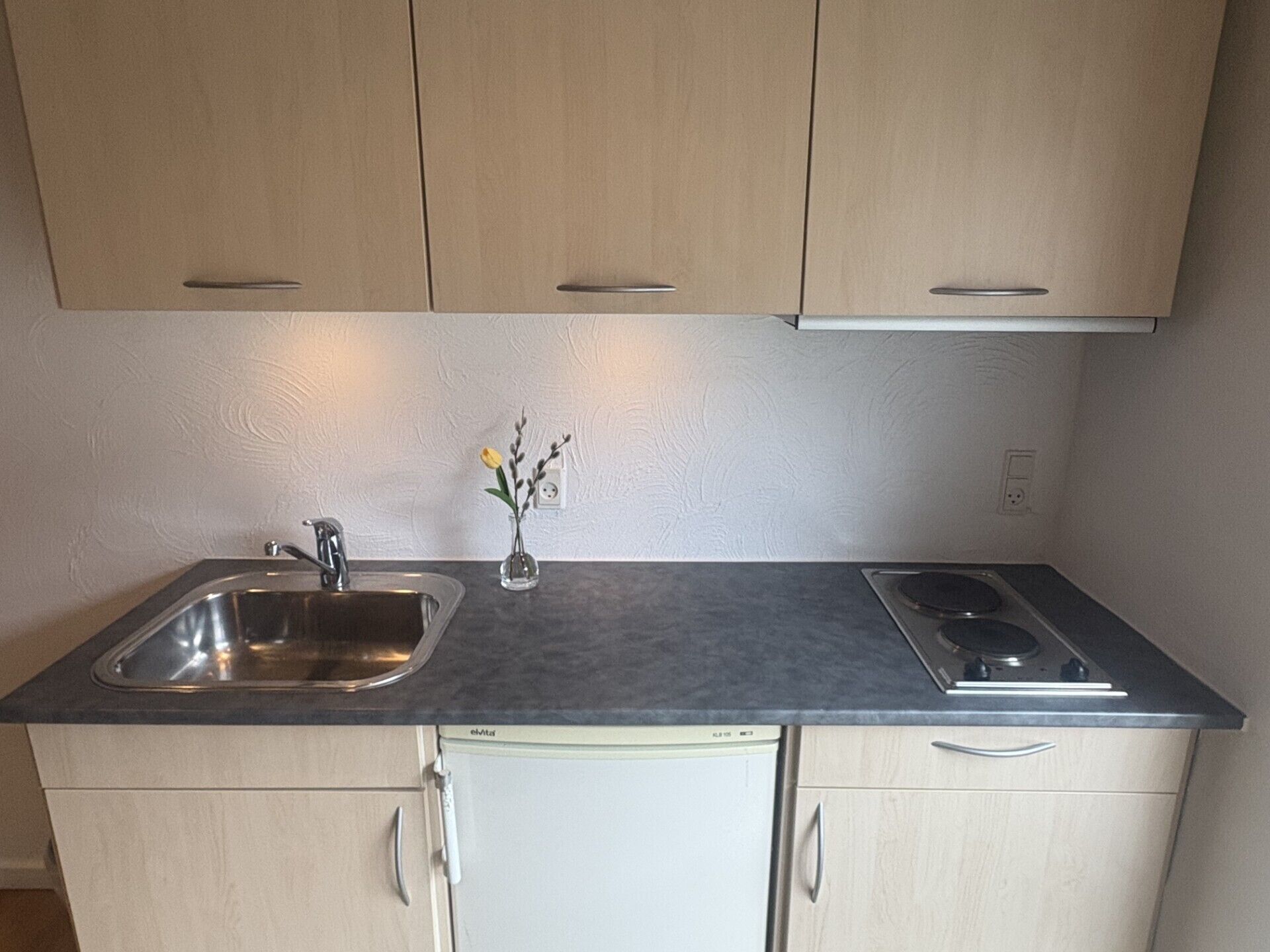 A kitchen with a sink, stove, and cabinets.