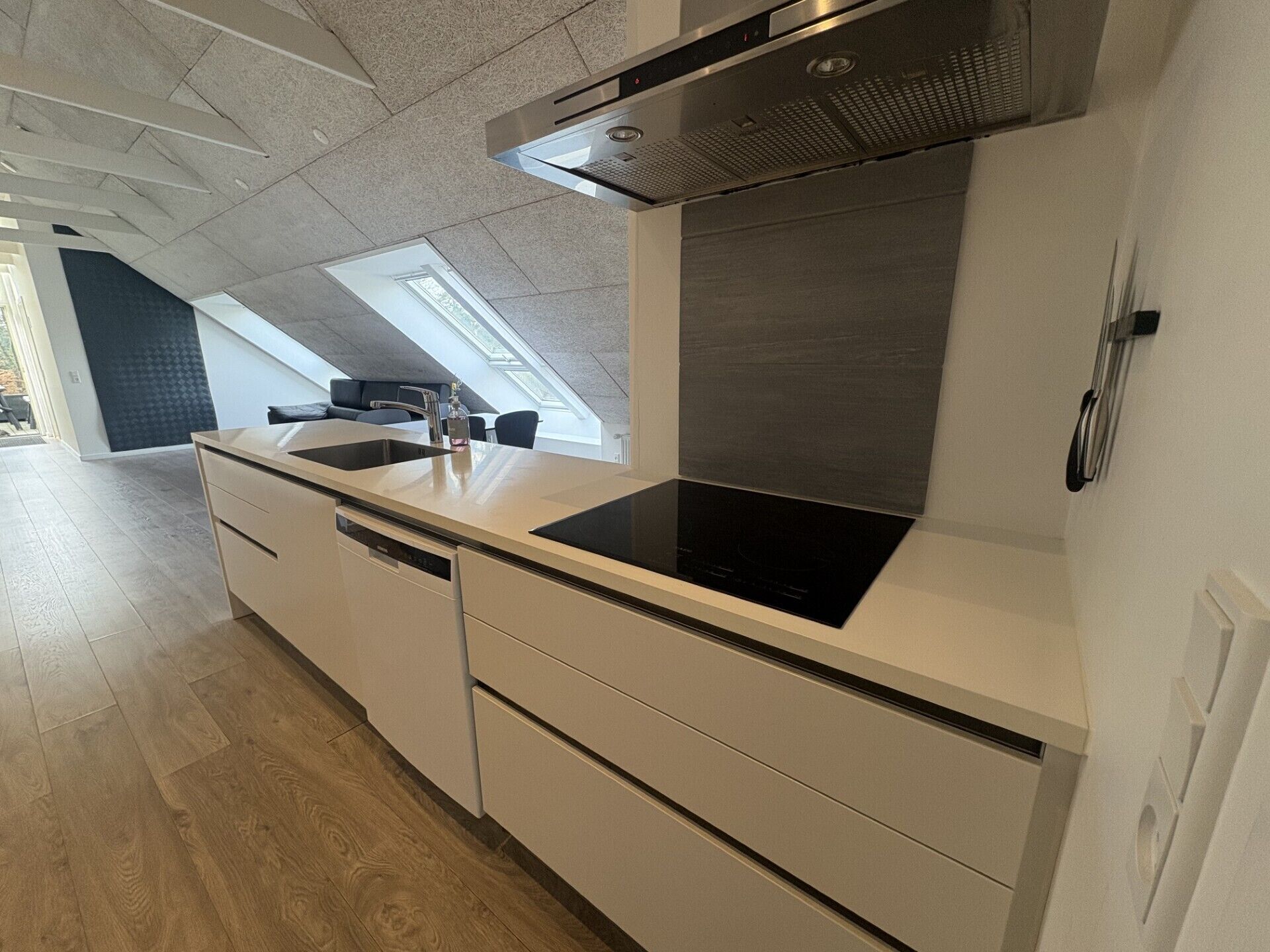 Una cocina moderna con estufa integrada, lavavajillas y un ventanal grande.