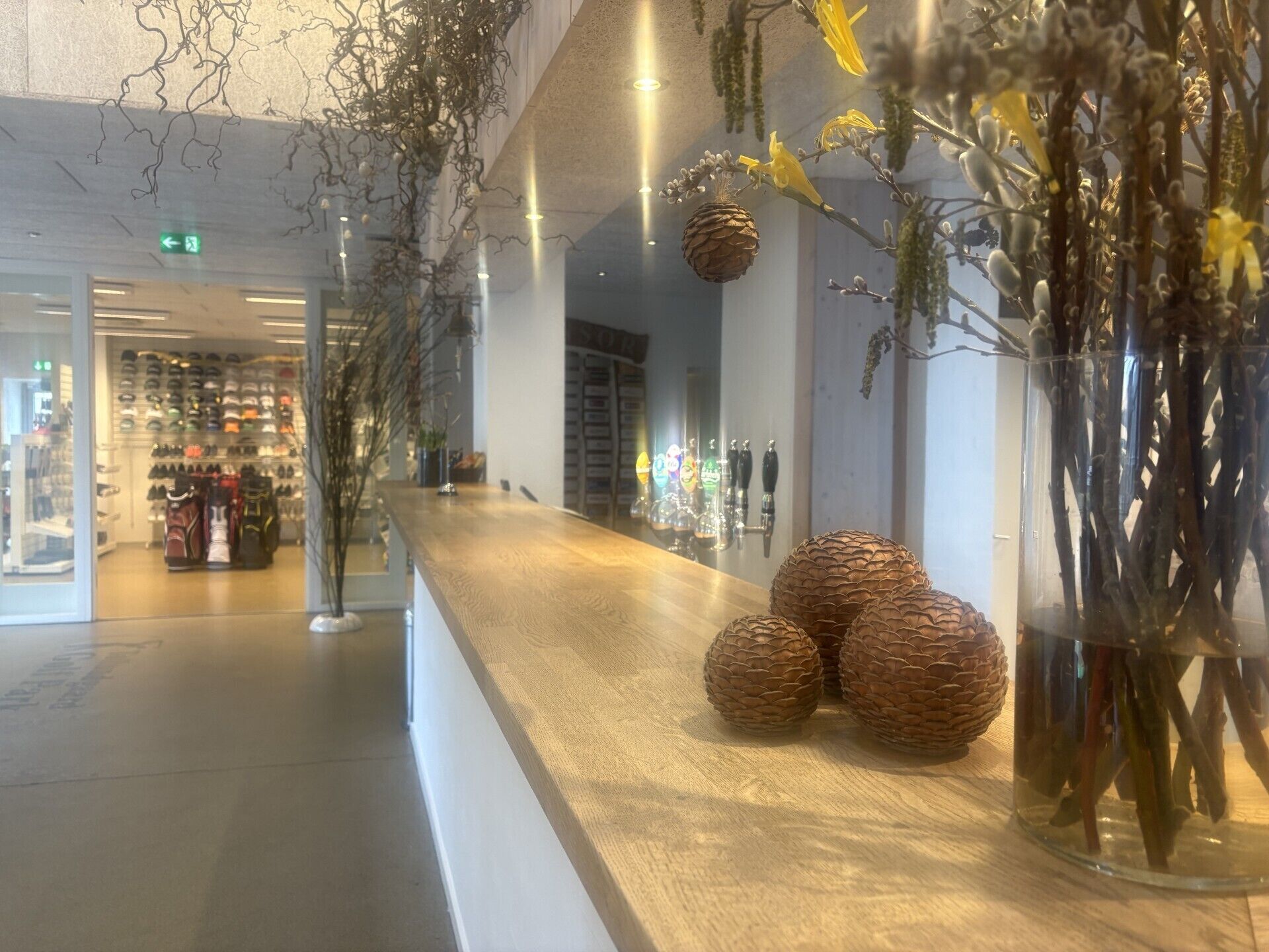 Ein modernes Interieur mit einem Holzbüro, dekorativen Kiefernzapfen und einer Glasvase mit Ästen.