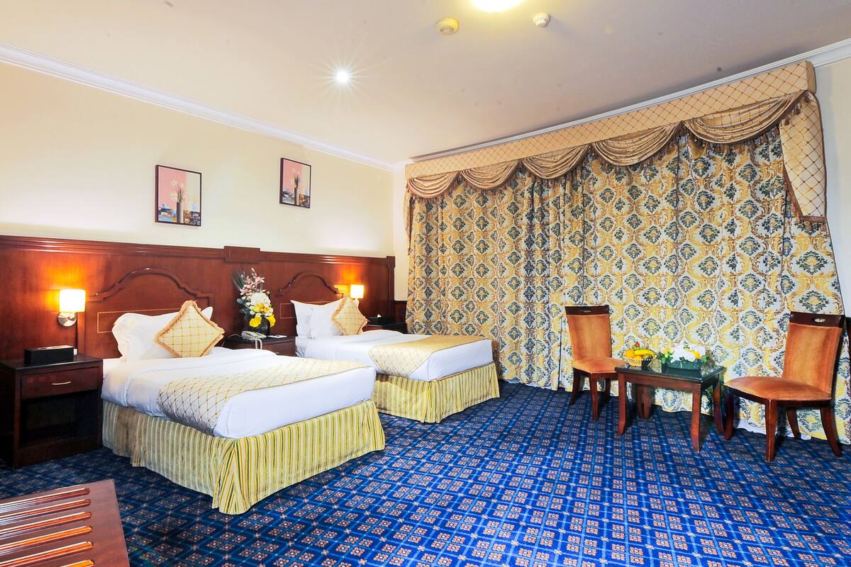 Une chambre d’hôtel avec deux lits, un bureau et des chaises.