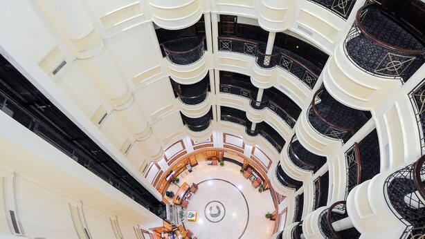 A multi-level atrium with a central circular seating area, multiple balconies, and a modern architectural design. - Ramee California Juffair (Manama)