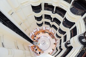 Un atrio de varios niveles con una zona de estar circular central, múltiples balcones y un diseño arquitectónico moderno.
