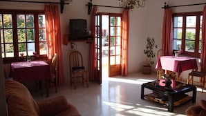 A living room with a sofa, a dining table, a TV, and a chandelier. - Anniko (Chania)