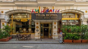 The exterior of the Tilia Hotel with a classic architectural style, featuring a prominent entrance, multiple flags, and a well-maintained outdoor seating area. - Tilia Hotel (Istanbul)