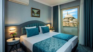 A hotel room with a large bed, a view of a historical building, and a small table with a vase of flowers. - Tilia Hotel (Istanbul)