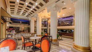 A hotel lobby with marble flooring, ornate columns, and a seating area with orange upholstered chairs. - Tilia Hotel (Istanbul)