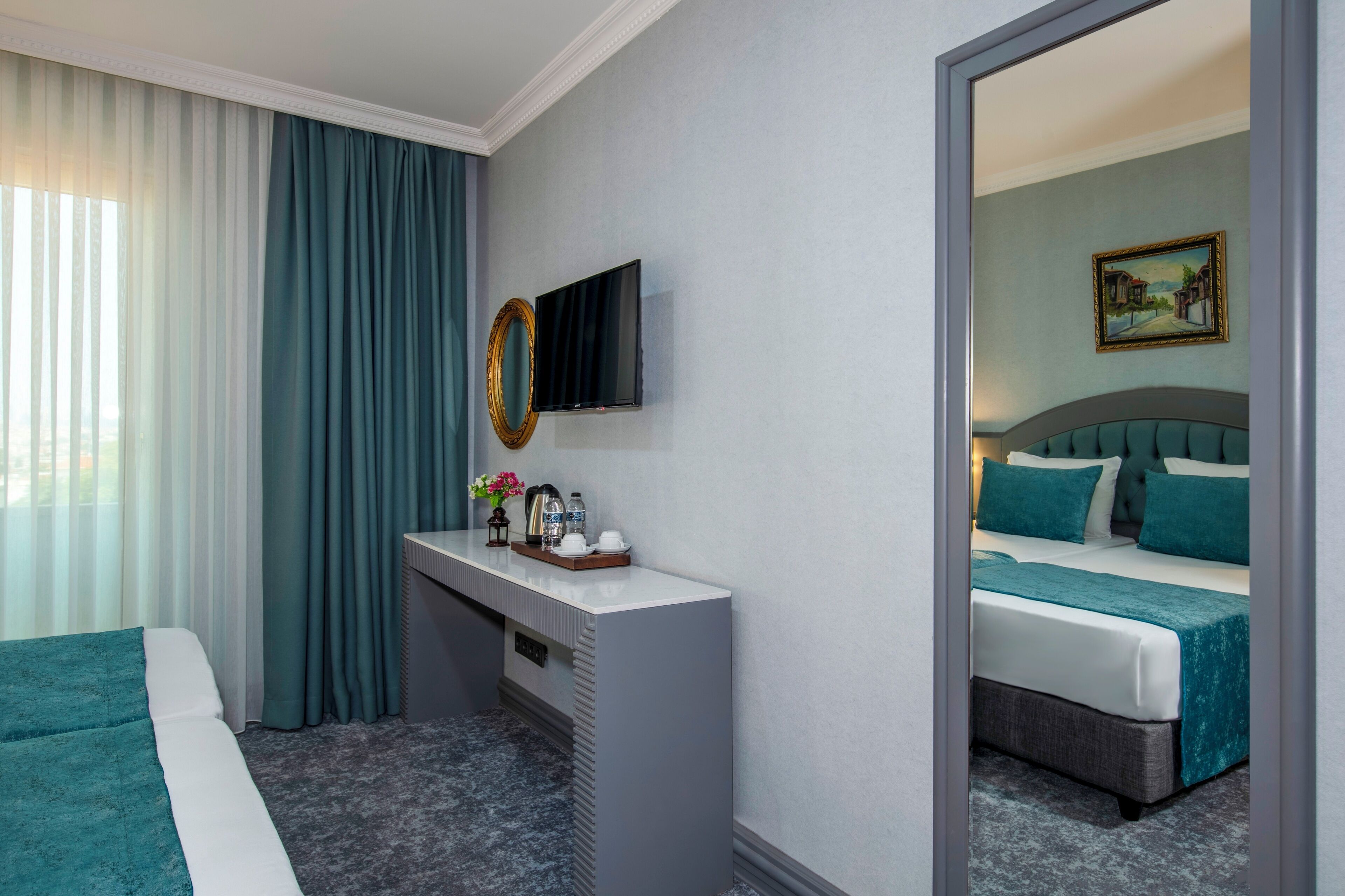 A hotel room with a bed, a desk, a television, and a painting on the wall.