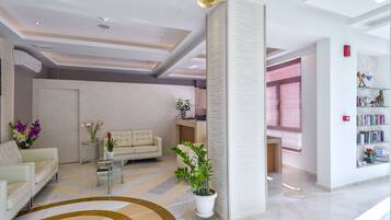 Un vestíbulo de hotel moderno con un sofá color crema, una mesita de centro y una planta en maceta.