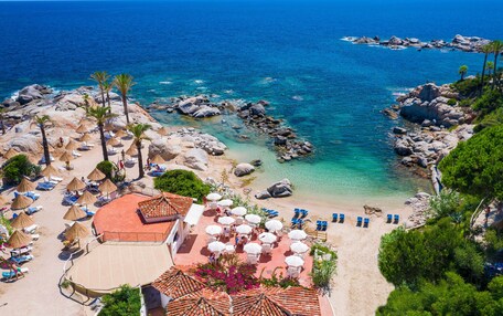 A beach resort with sun loungers, umbrellas, and a pool area.