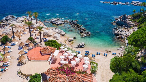 Un resort frente al mar con tumbonas, sombrillas y una zona de piscina.