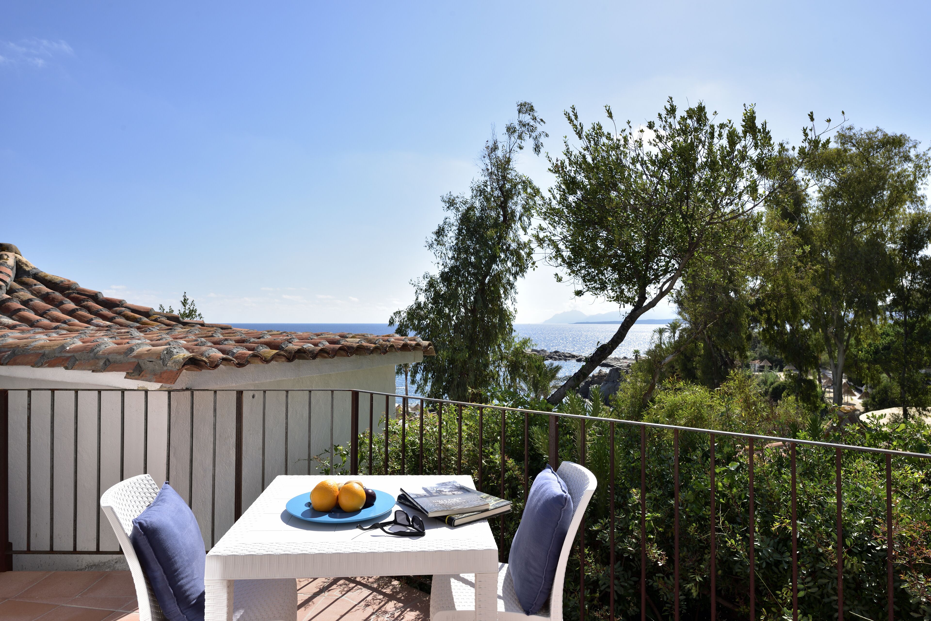 Ein Balkon mit Tisch für zwei Personen, mit Blick auf eine malerische Aussicht auf Meer und Hügel.