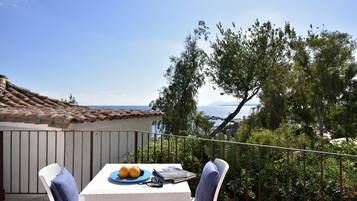 Ein Balkon mit Tisch für zwei Personen, mit Blick auf eine malerische Aussicht auf Meer und Hügel.
