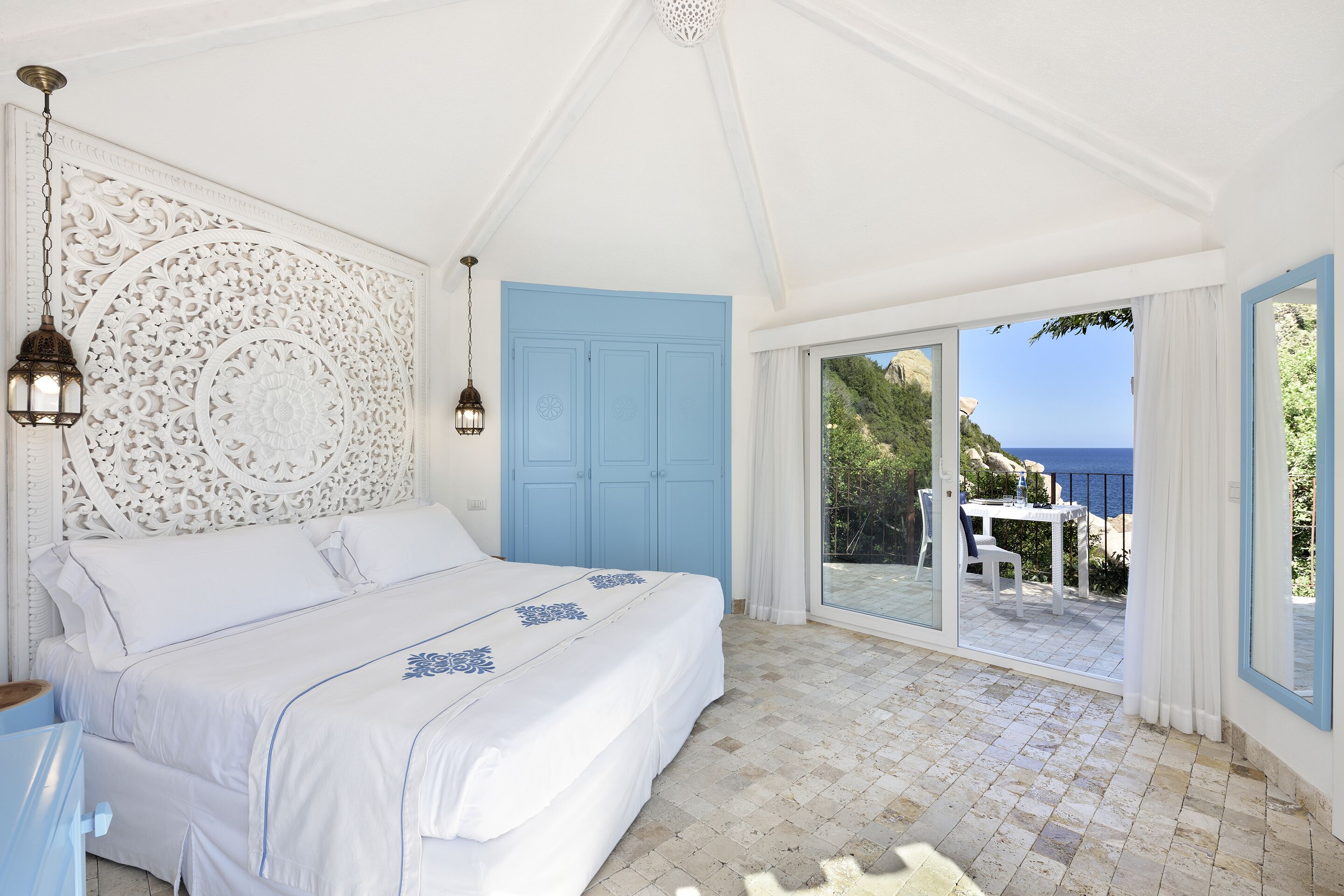 Una camera da letto con un letto, una porta blu e vista mare.