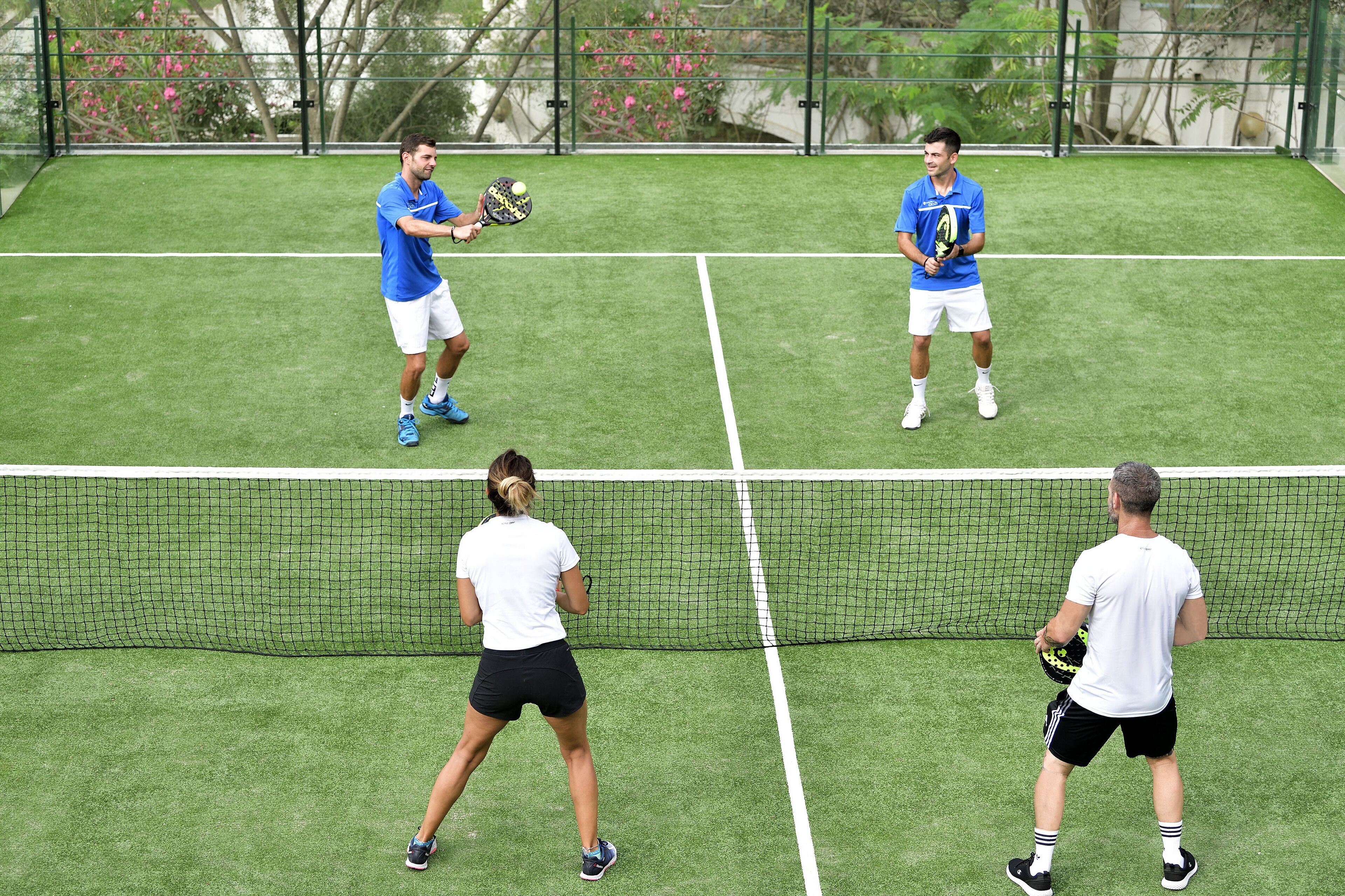 Una cancha de tenis con cuatro jugadores en juego.