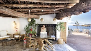 Un espace extérieur rustique aménagé avec une table en bois, des chaises et un ordinateur portable.
