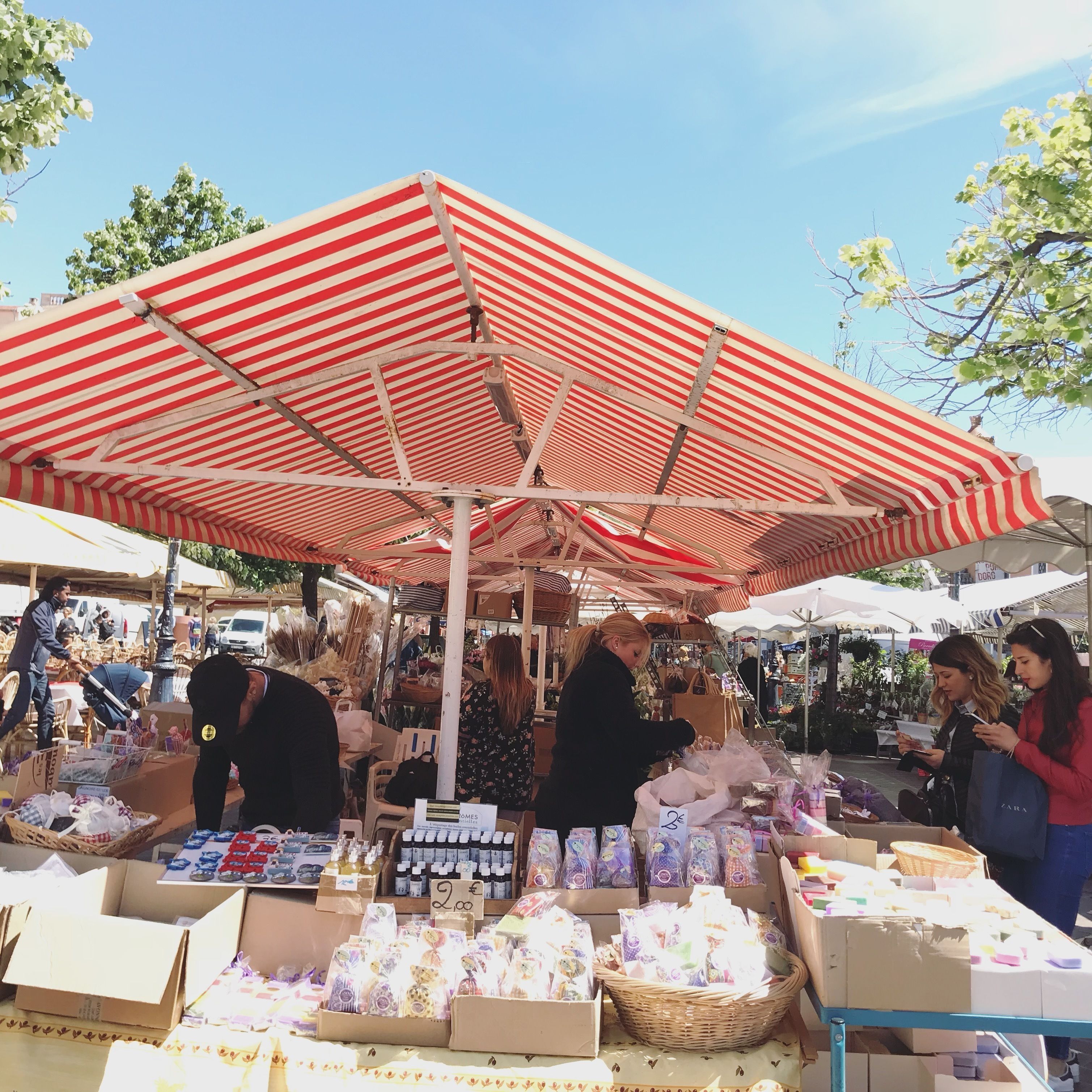 A market stall with various goods under a striped canopy.