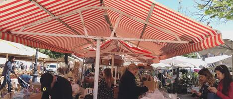 A market stall with various goods under a striped canopy.