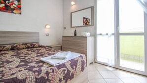 Un dormitorio con una cama grande, un aparador, un espejo y un balcón con vistas.