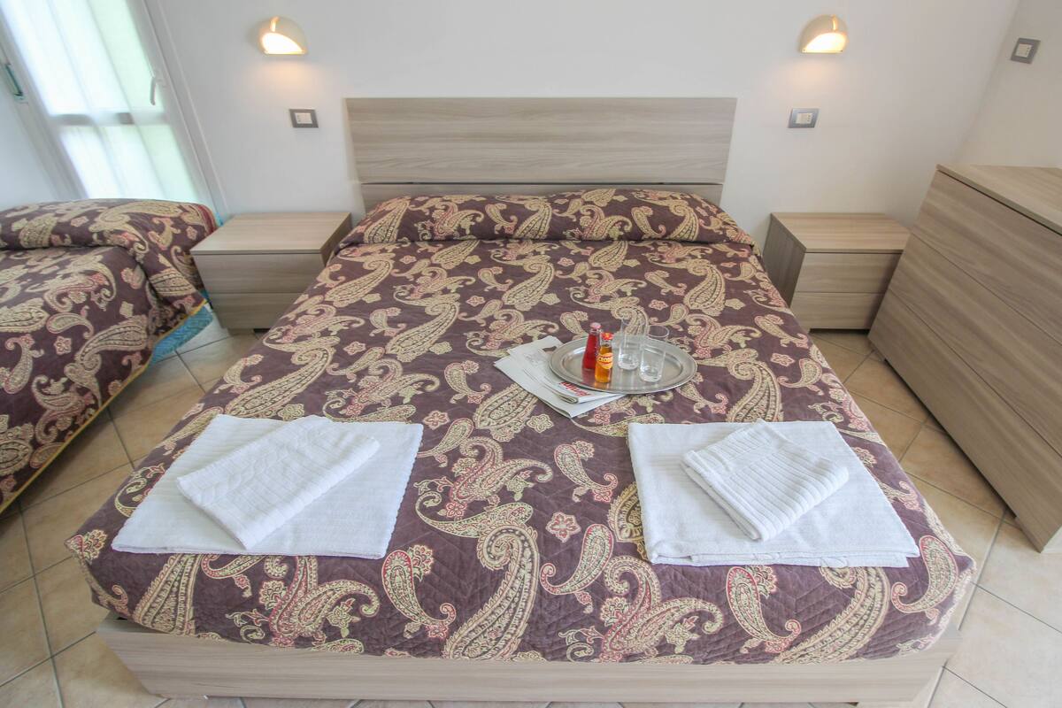 A hotel room with a large bed, two bedside tables, a nightstand, and a dresser.