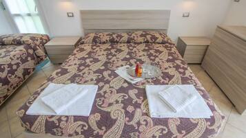 Une chambre d’hôtel avec un grand lit, deux tables de chevet, une petite table et une commode.