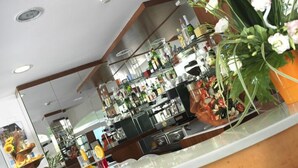 Un área de bar moderna con una barra curva, vitrinas de cristal y una variedad de botellas y vasos.