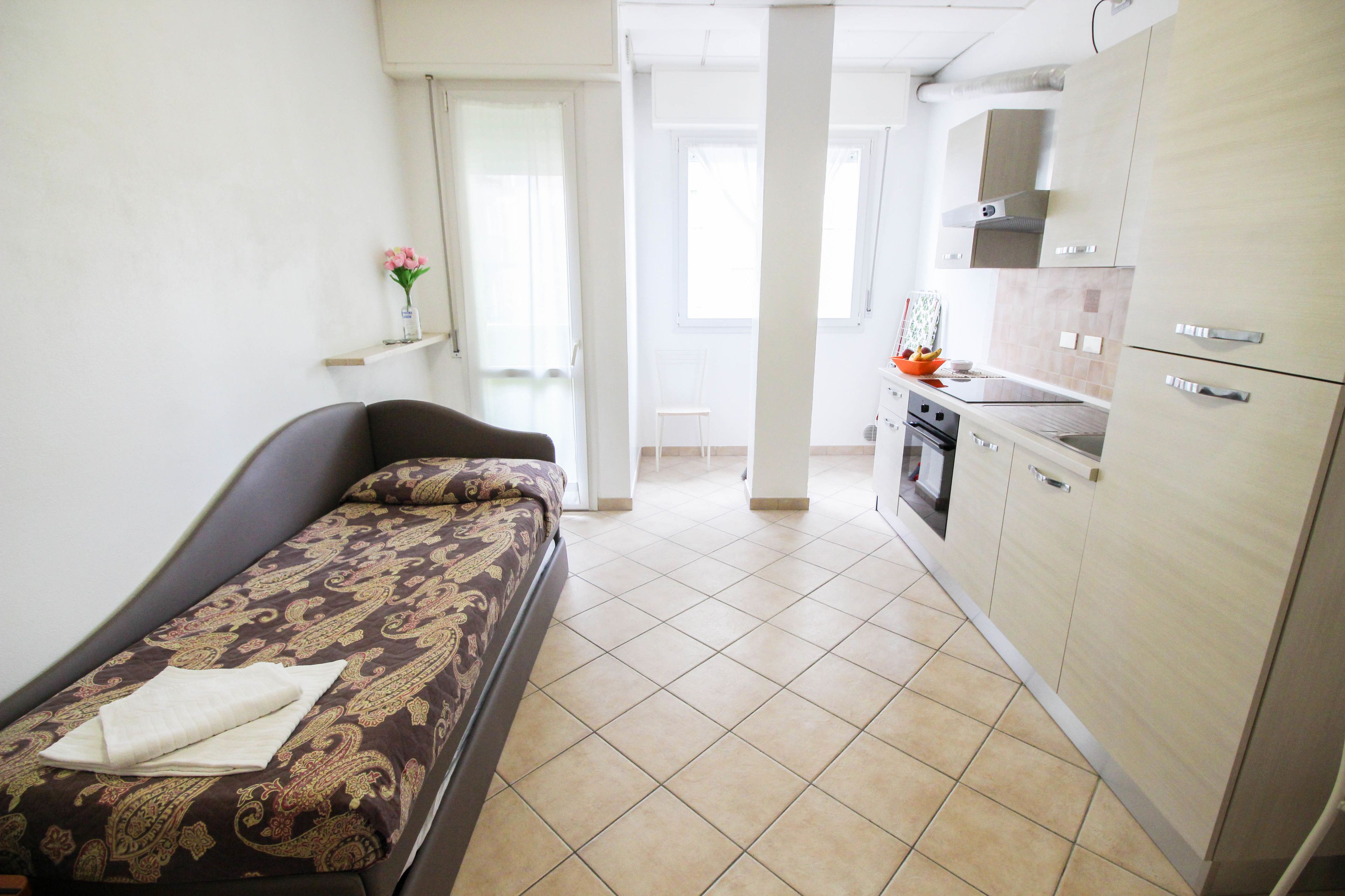Een compacte kamer met een bed, een klein kitchenette en een badkamer.