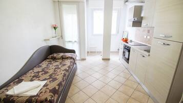 Een compacte kamer met een bed, een klein kitchenette en een badkamer.