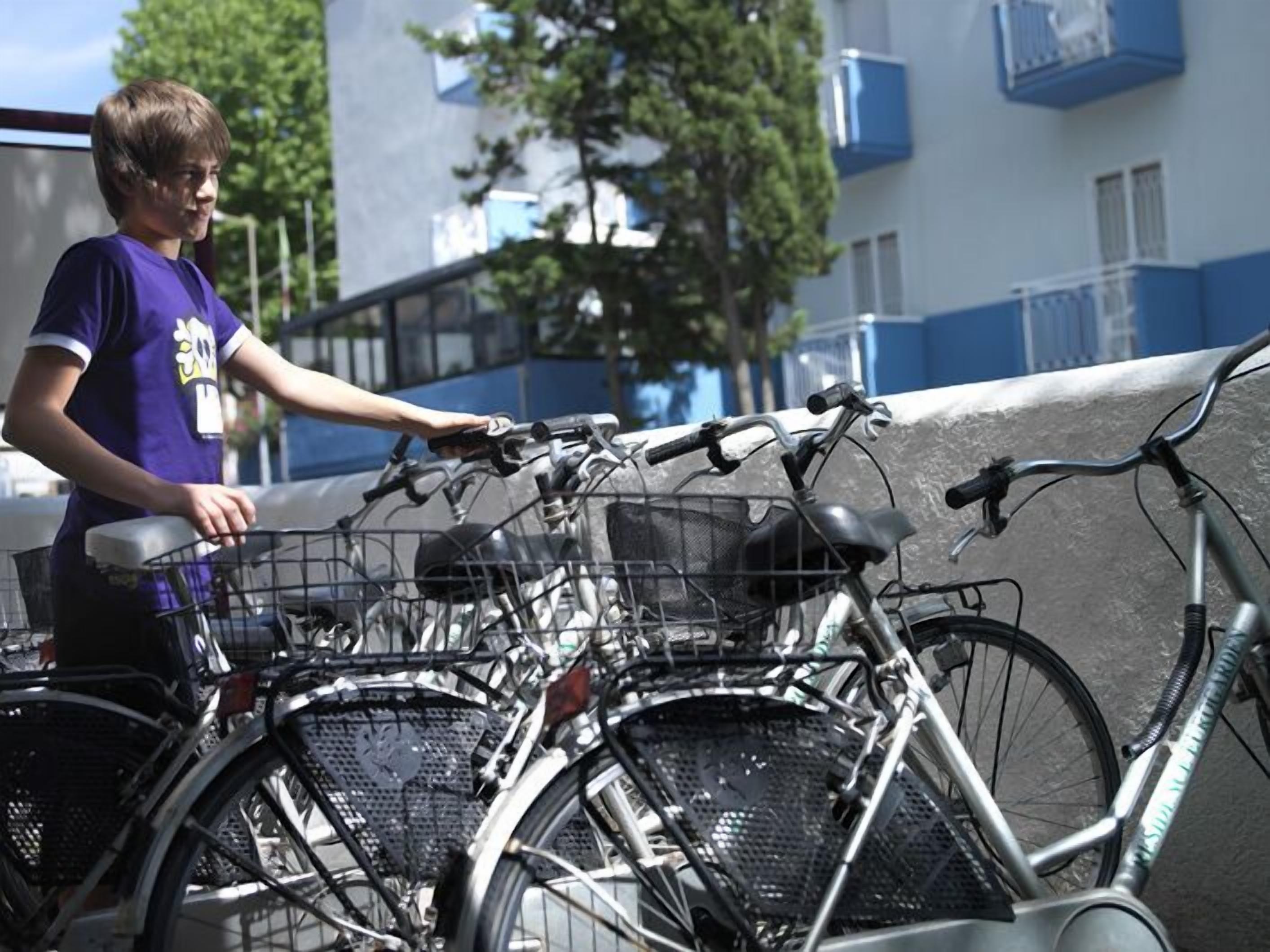 A person leaning on a bicycle rack with multiple bicycles parked.