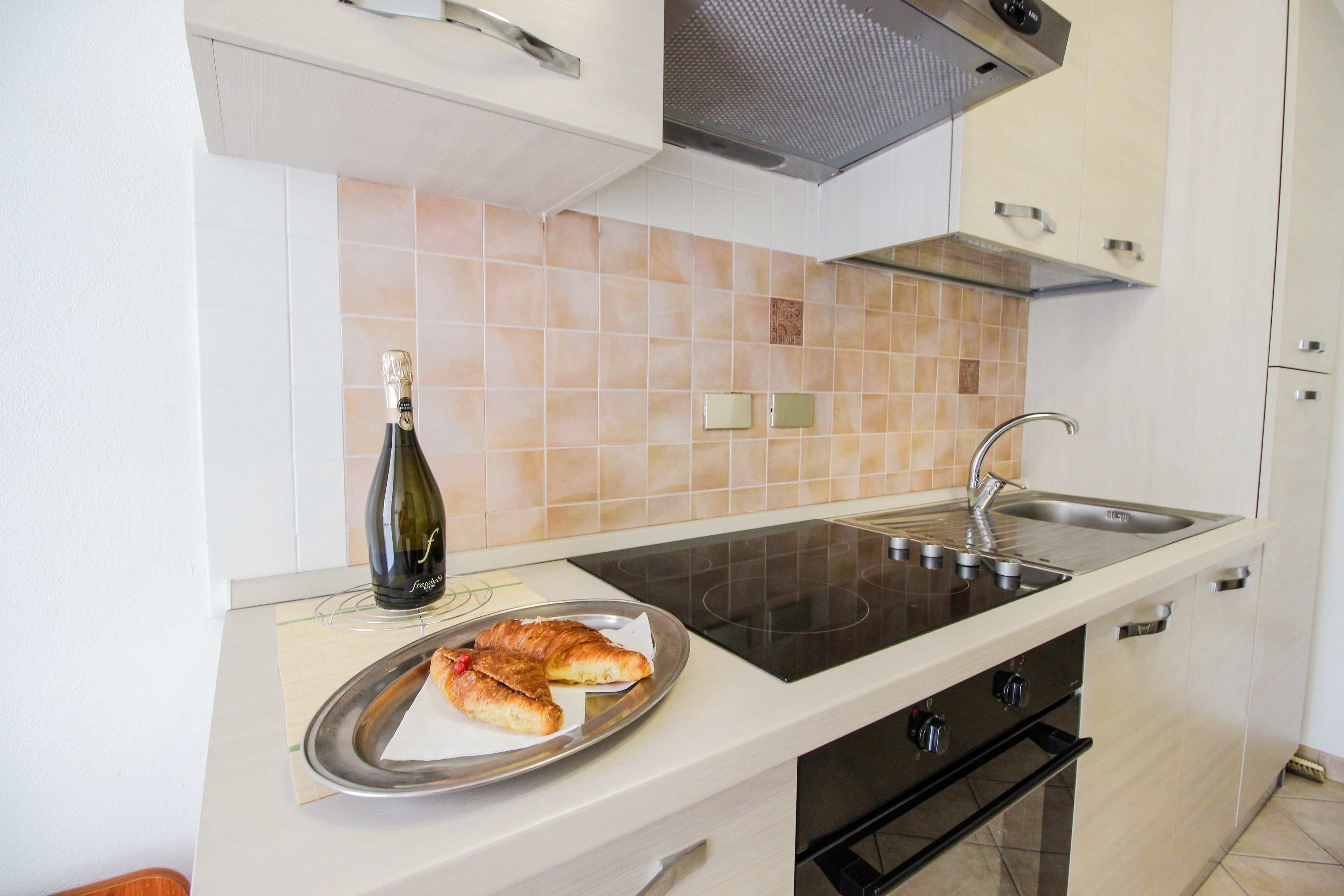 Una cocina con estufa, pileta y una botella de champán sobre la encimera.