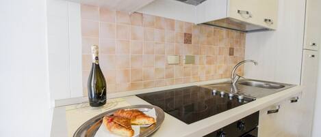 Una cocina con estufa, pileta y una botella de champán sobre la encimera.