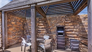 An outdoor patio with stone walls, wooden beams, and a grill area. - Holiday Inn Express & Suites Rockport - Bay View by IHG (Rockport)