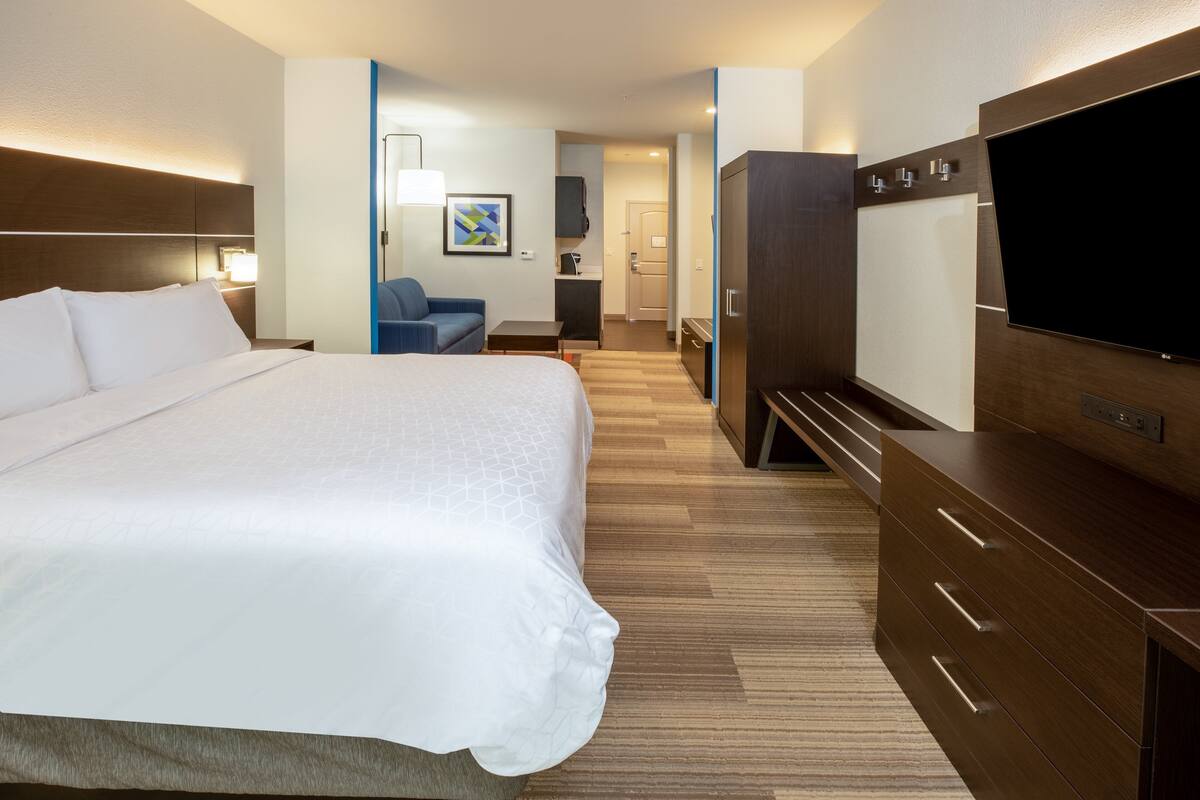Una habitación de hotel con una cama grande, un escritorio, una silla, un televisor y un armario.