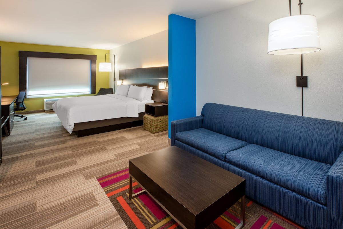 Una habitación de hotel con cama, sofá, escritorio y lámpara.