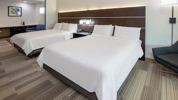 Quarto de hotel com duas camas, uma escrivaninha, uma cadeira e um abajur.