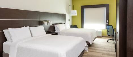 A hotel room with two beds, a desk, a chair, and a lamp.