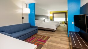 A hotel room with a blue sofa, a bed with white linens, a TV, and a desk. - Holiday Inn Express & Suites Rockport - Bay View by IHG (Rockport)
