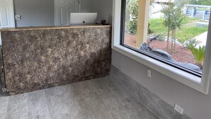 A kitchen with a granite countertop, a white door, and a window with a view of a garden. - Savannah Inn and Suites (Garden City)